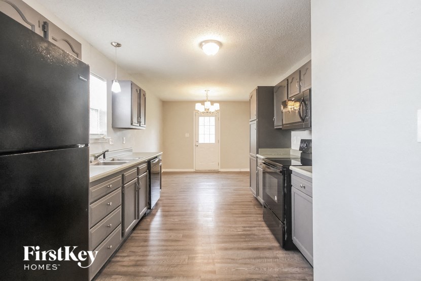 an empty kitchen with black appliances and white cabinets