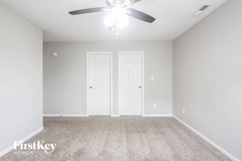 an empty room with a ceiling fan and white doors
