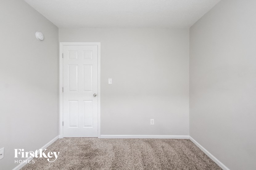 a bedroom with a white door and a carpeted floor