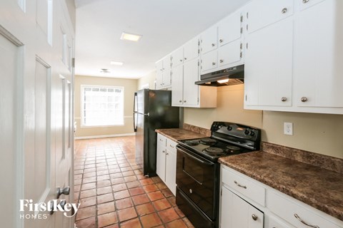 A kitchen with white cabinets and a black stove top oven.