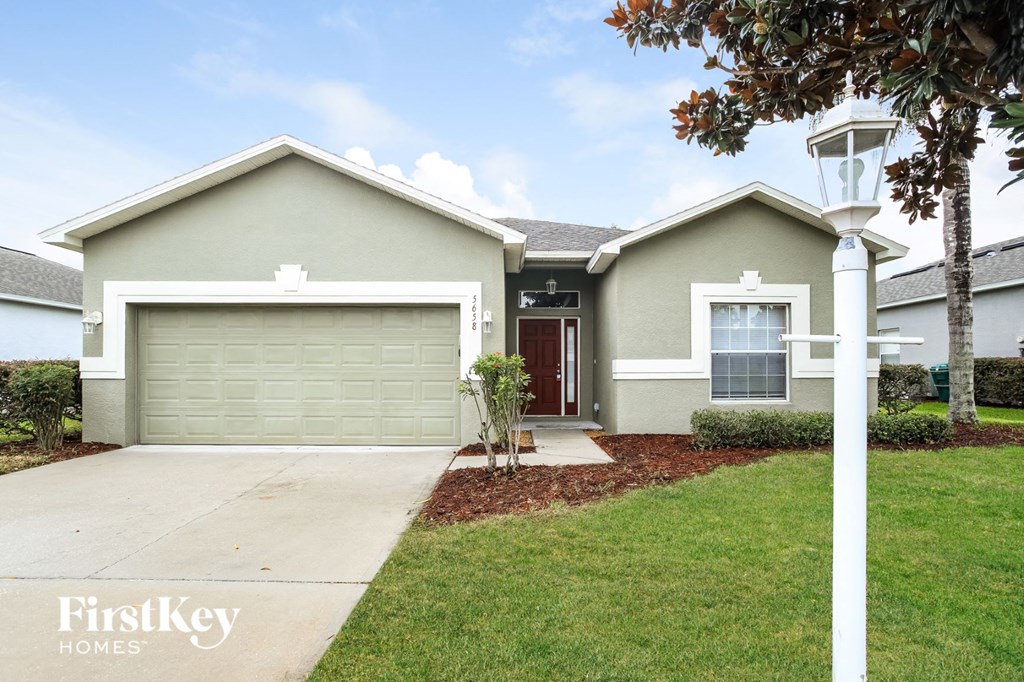A house with a garage and a tree in front of it.