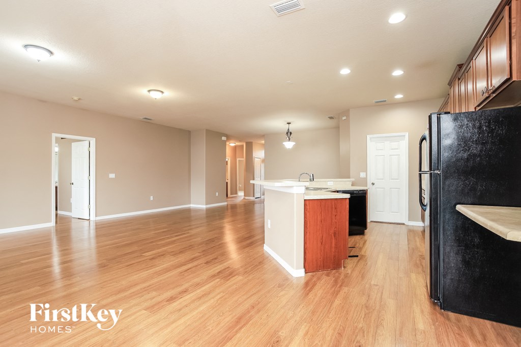 A kitchen with wooden floors and a black refrigerator.