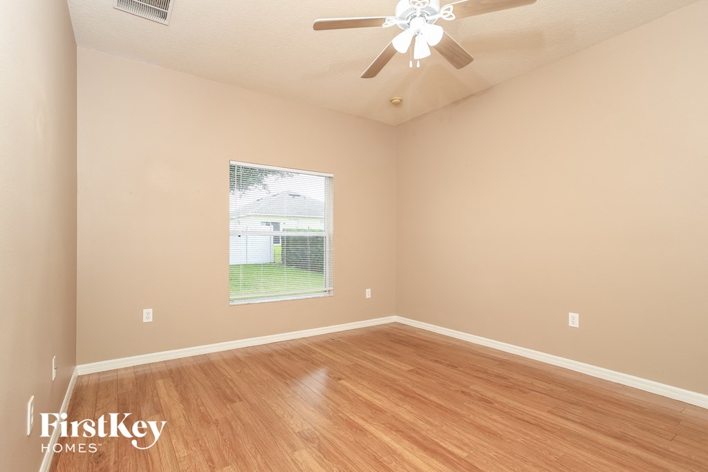 Empty room with wooden floor and a ceiling fan.