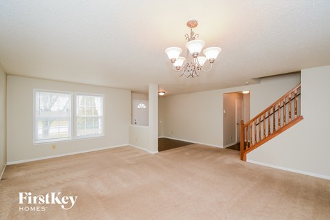 A spacious room with a chandelier and a staircase.