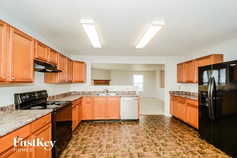 A kitchen with orange cabinets and black appliances.
