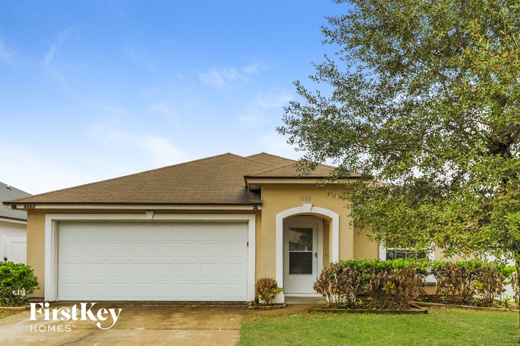 A house with a garage door and a tree in front.