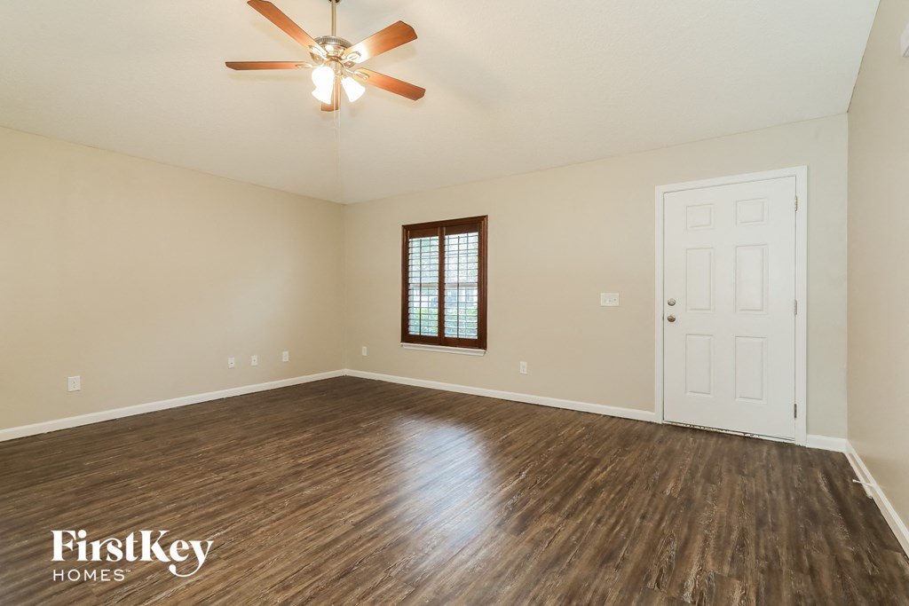 A room with a ceiling fan and wooden flooring.