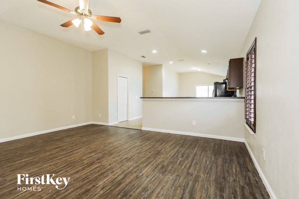 A spacious room with a ceiling fan and wooden flooring.