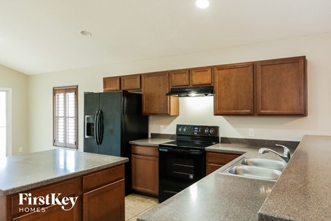 A kitchen with a black refrigerator and wooden cabinets.