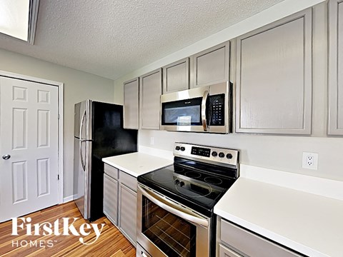 A kitchen with a black fridge and stove top oven.