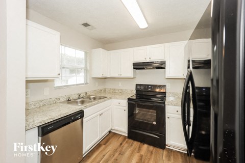 a kitchen with white cabinets and black appliances