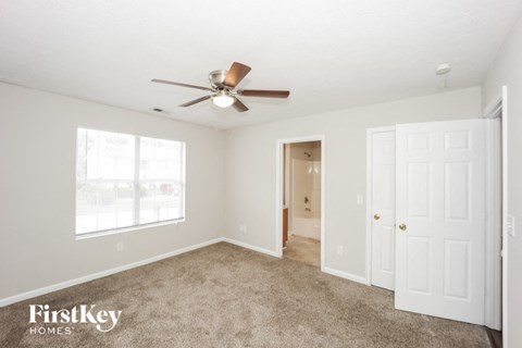 a living room with carpet and a ceiling fan