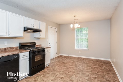 a kitchen with white cabinets and black appliances and a window