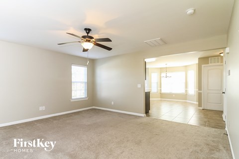 A spacious room with a ceiling fan and a door leading to another room.