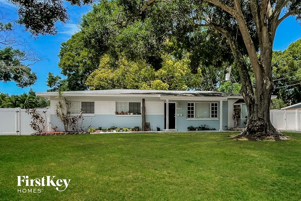 A house with a white fence and a tree in front of it.