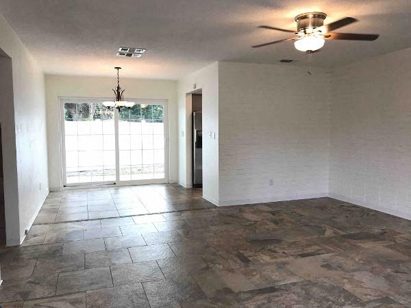 A room with a ceiling fan and sliding glass doors.
