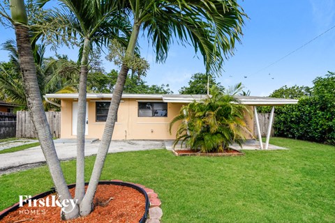 a small yellow house with palm trees in front of it
