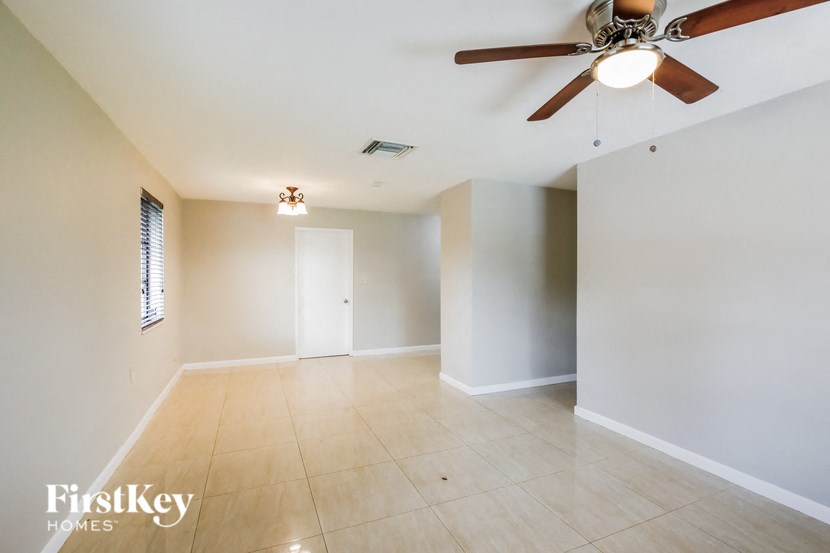 a empty living room with a ceiling fan and tiled floors