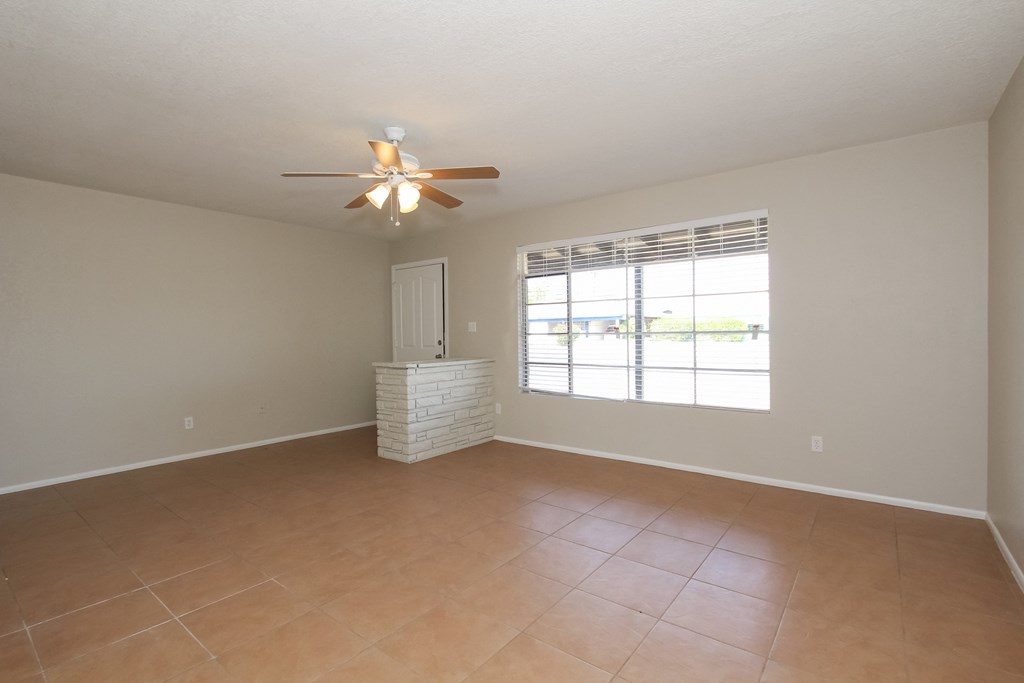 A room with a ceiling fan and a window with blinds.