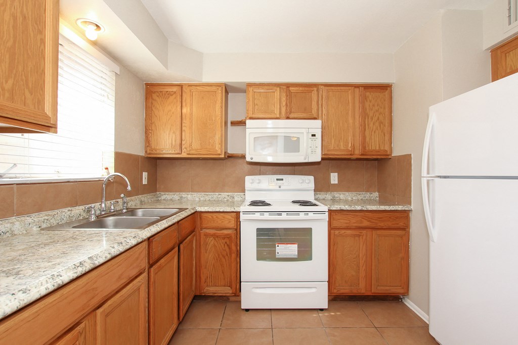 A kitchen with a white refrigerator, white stove, and brown cabinets.