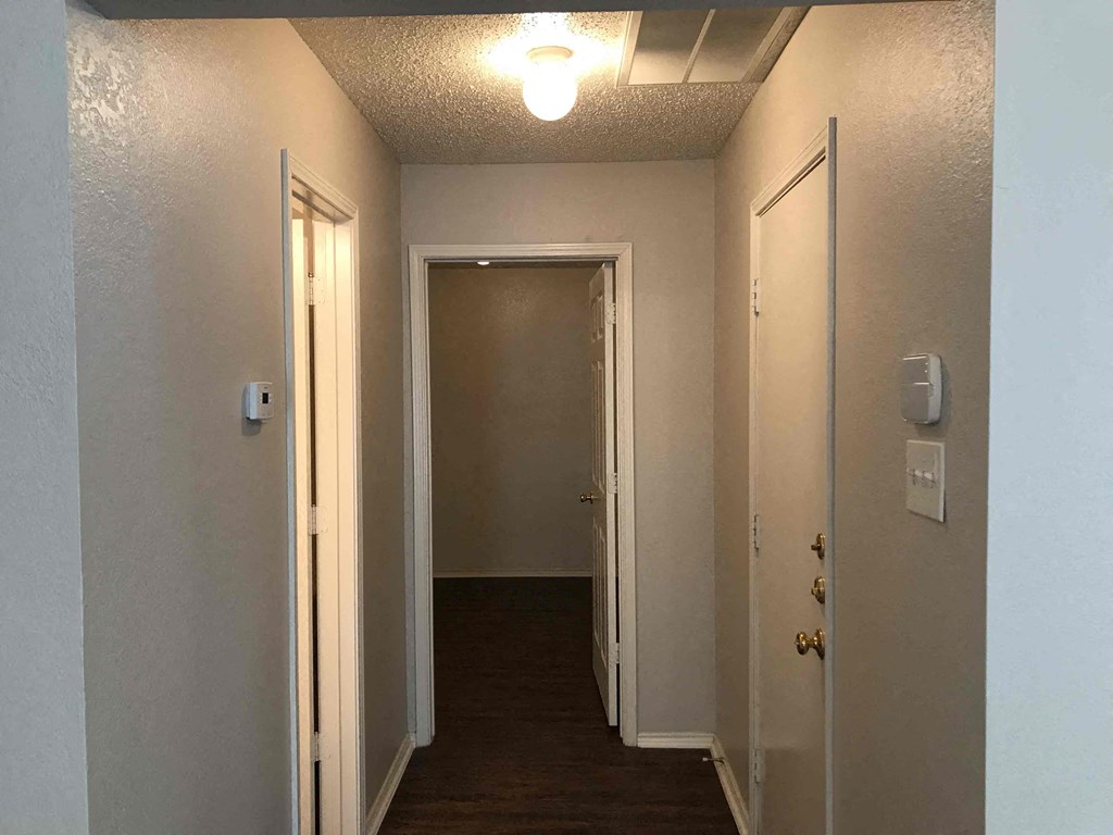 A hallway with a light on the ceiling and doors on both sides.