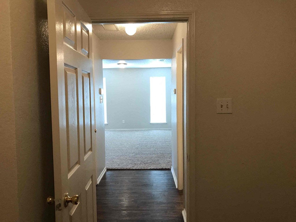 A hallway with a rug on the floor and a door on the left.