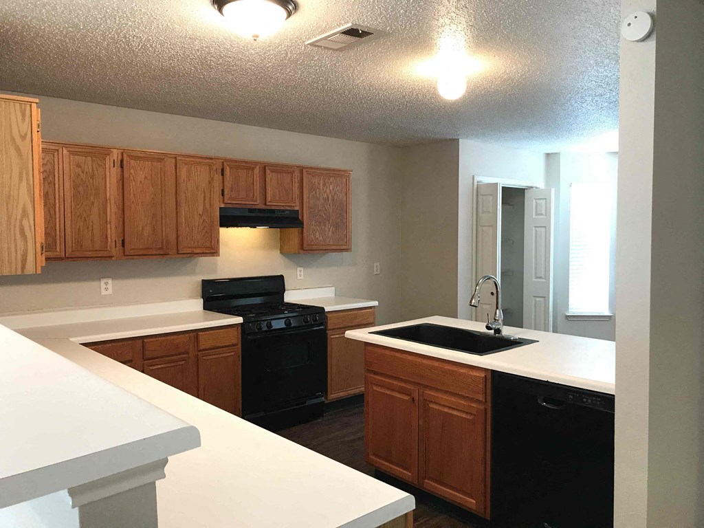 A kitchen with wooden cabinets and black appliances.