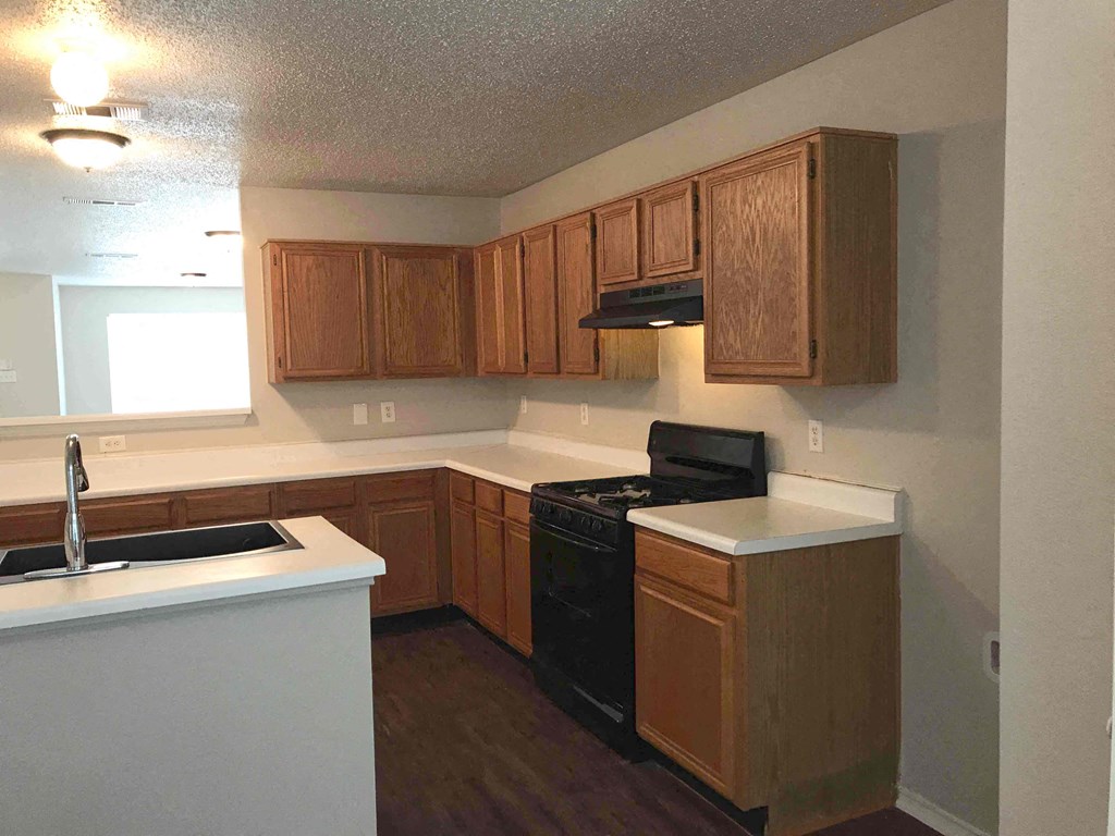 A kitchen with wooden cabinets and a black stove top oven.