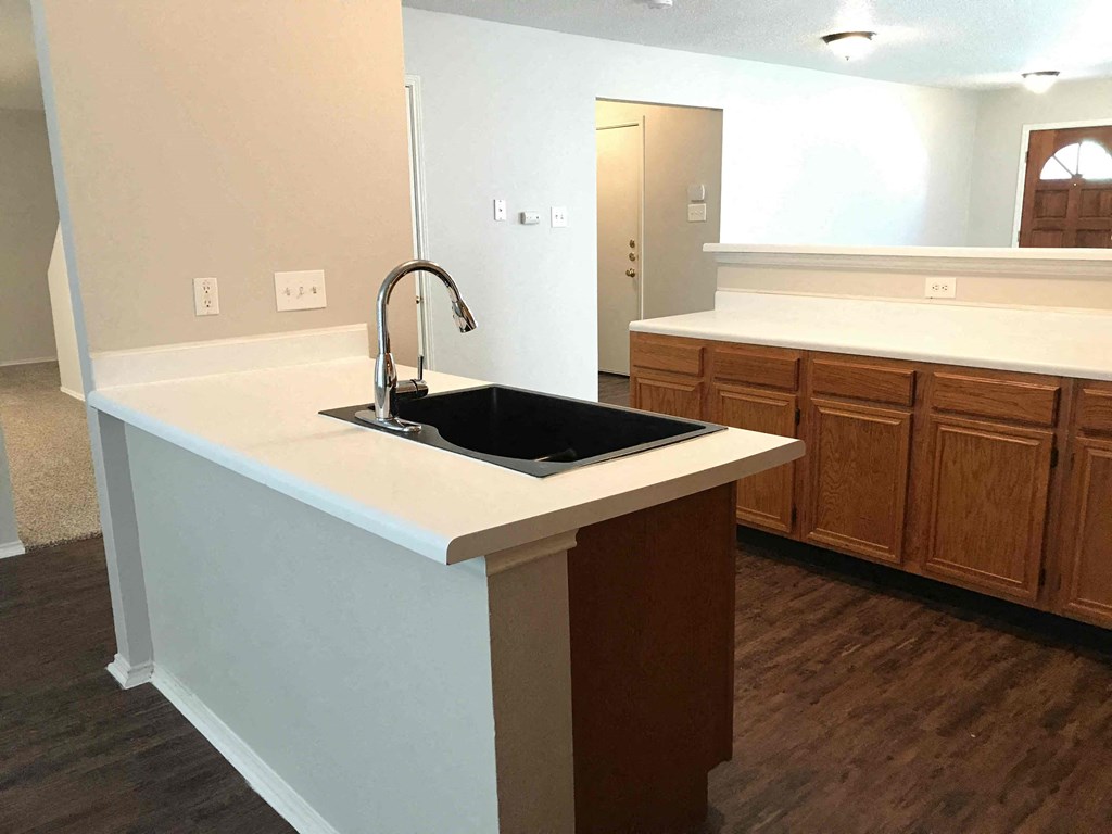 A kitchen with a sink and wooden cabinets.