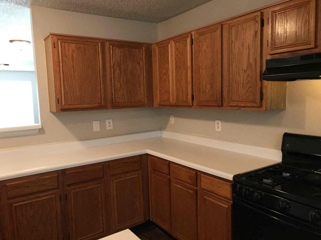A kitchen with wooden cabinets and a black stove.