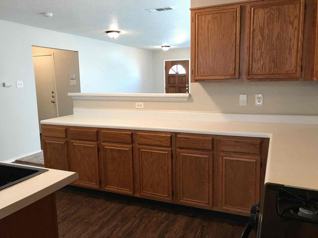 A kitchen with wooden cabinets and a white counter.