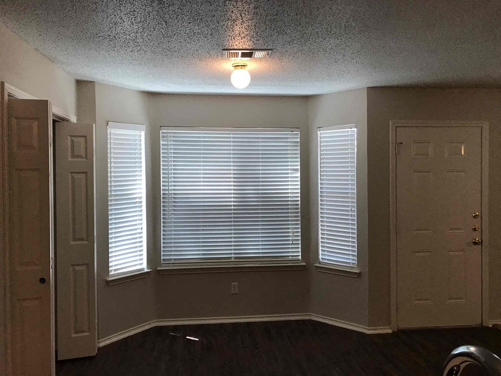 A room with a light on the ceiling and a window with blinds.