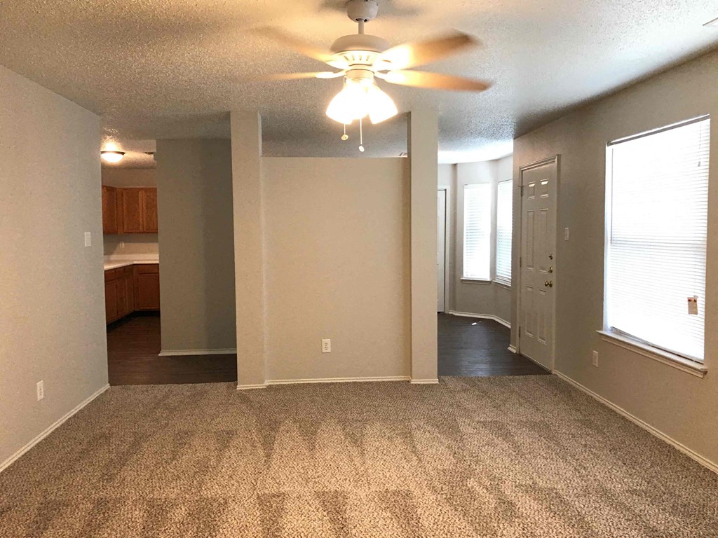 A room with a ceiling fan and carpeted floor.