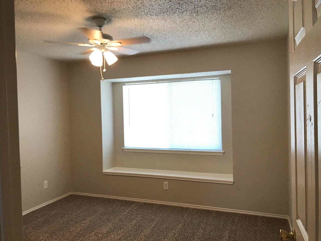 A room with a ceiling fan and a window.