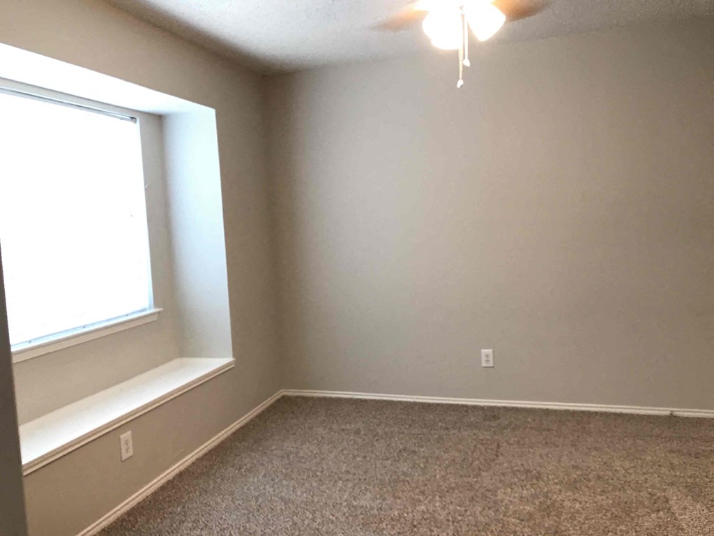 A room with a window and carpeted floor.
