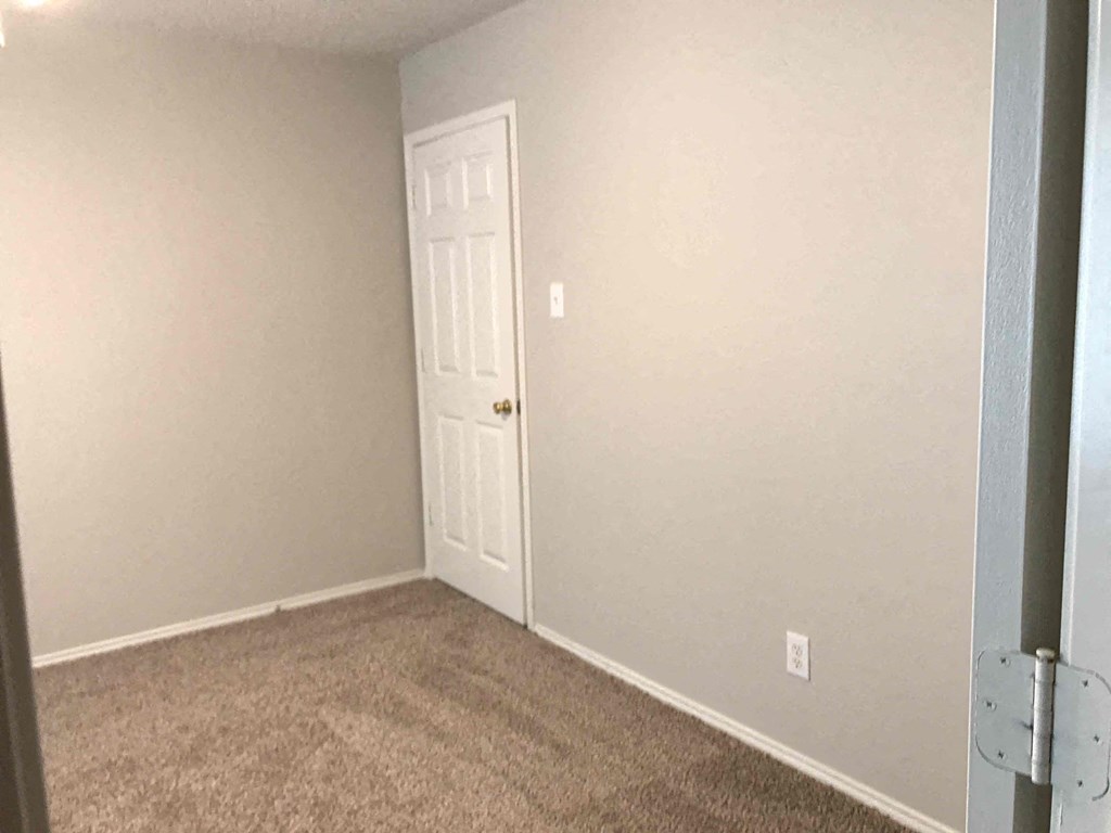 A room with a white door and carpeted floor.