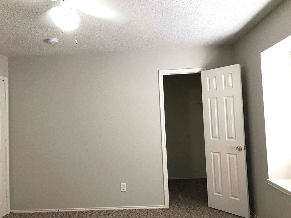 A room with a door on the right and a wall socket on the left.