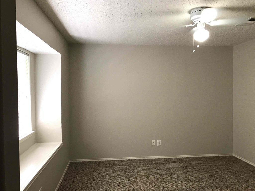 A room with a carpeted floor and a window on the left side.