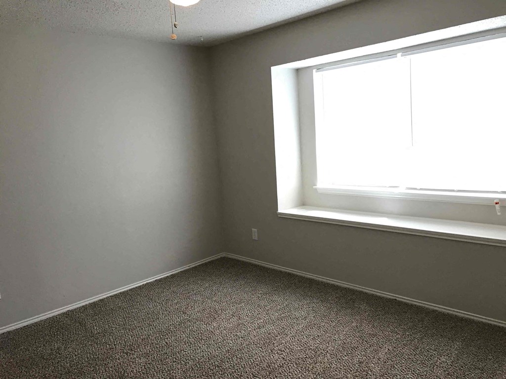 A room with a window and carpeted floor.