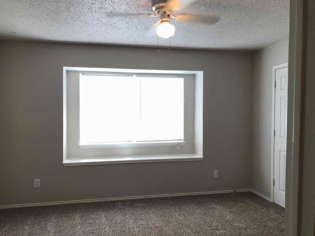 A room with a window and a ceiling fan.