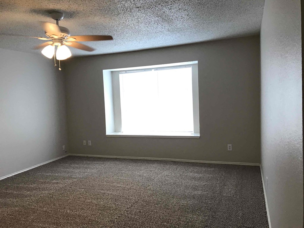 A room with a ceiling fan and a window.