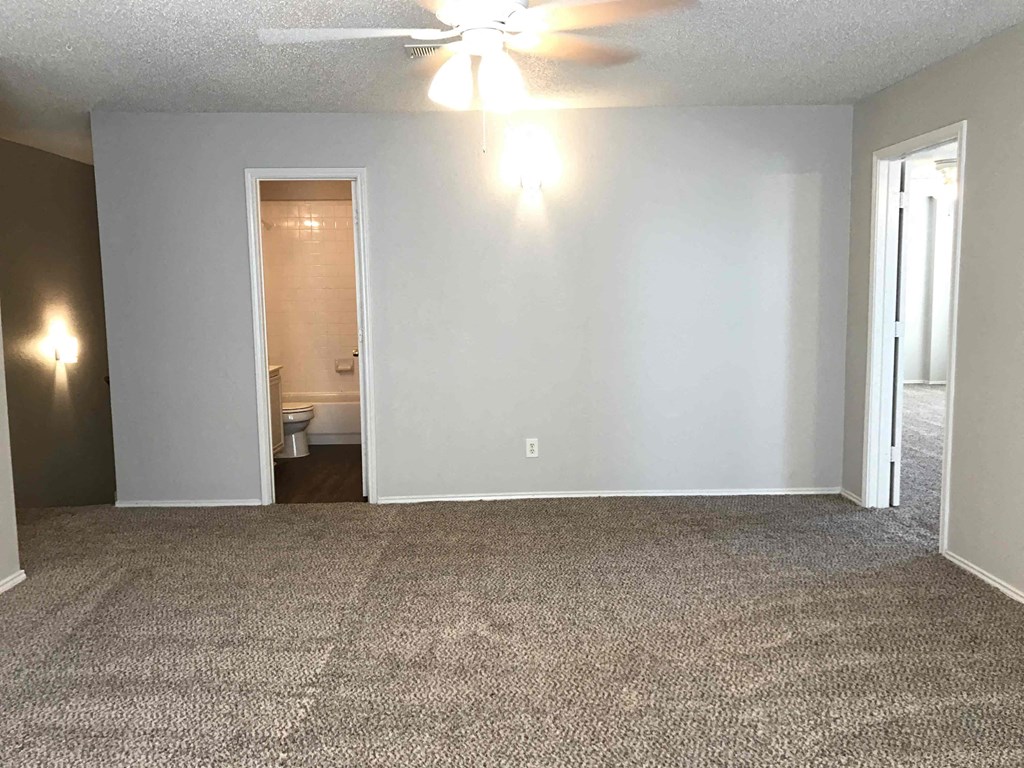 A room with a carpeted floor and a ceiling fan.