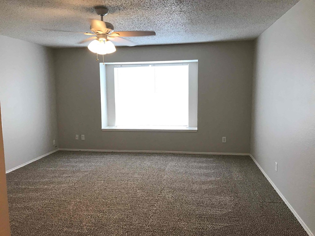 A room with a ceiling fan and carpeted floor.