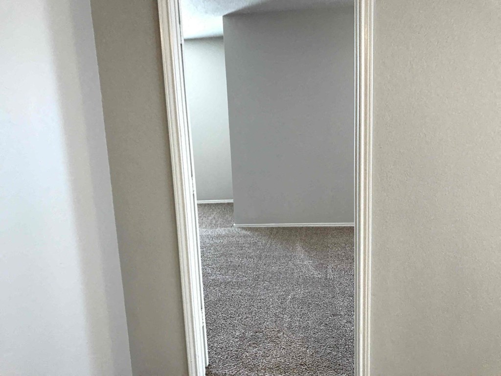 A carpeted hallway with a white door on the left.
