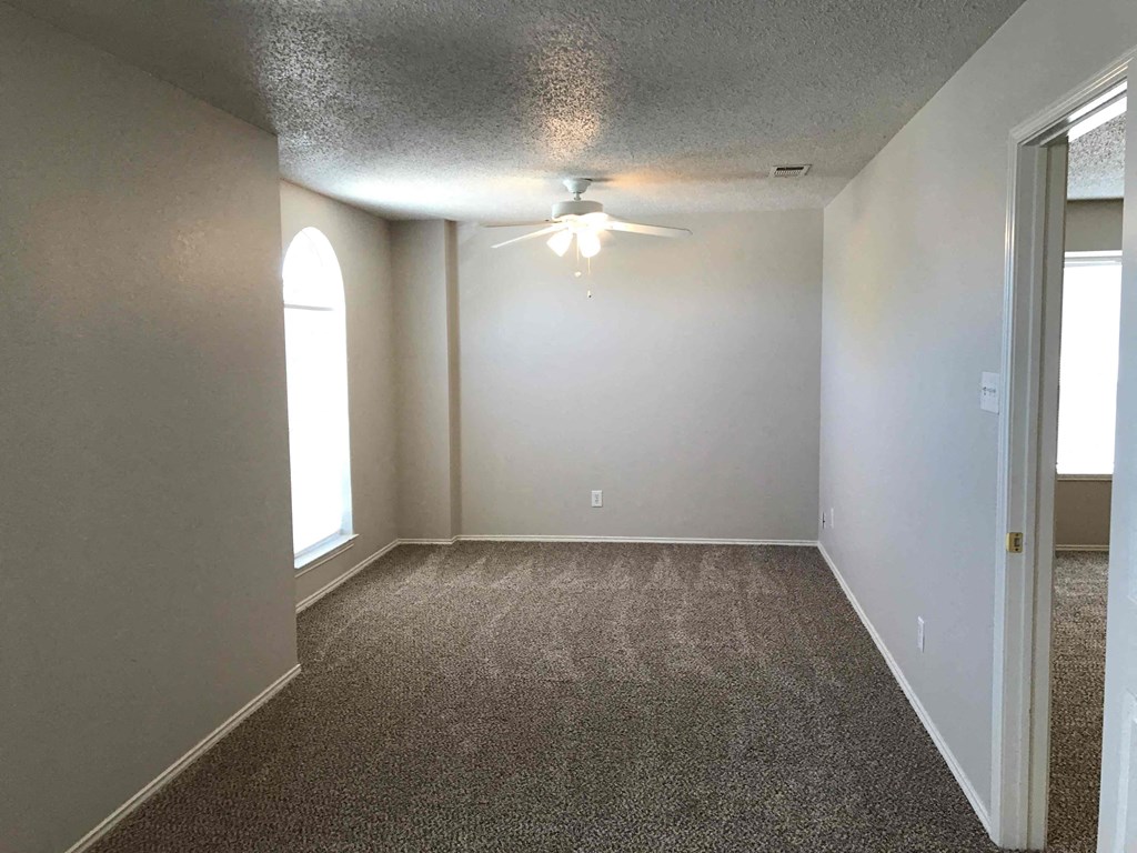 A room with a ceiling fan and carpeted floor.