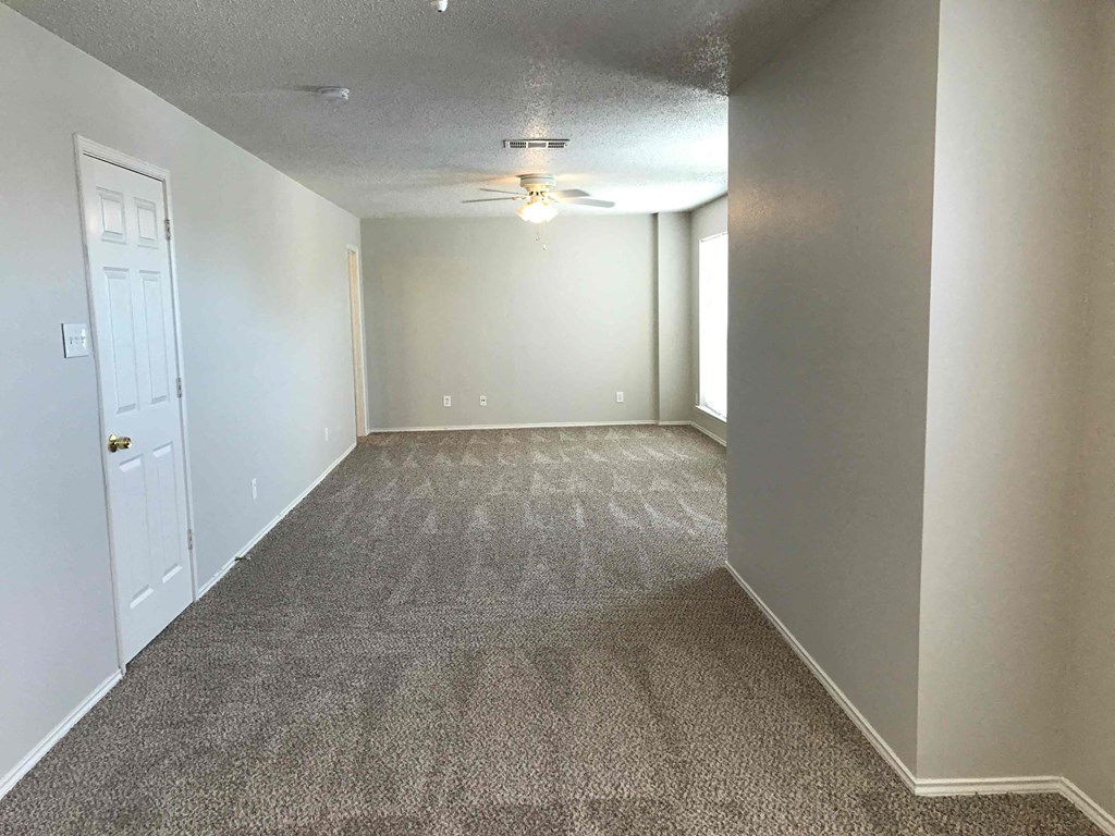 A room with a carpeted floor and a ceiling fan.