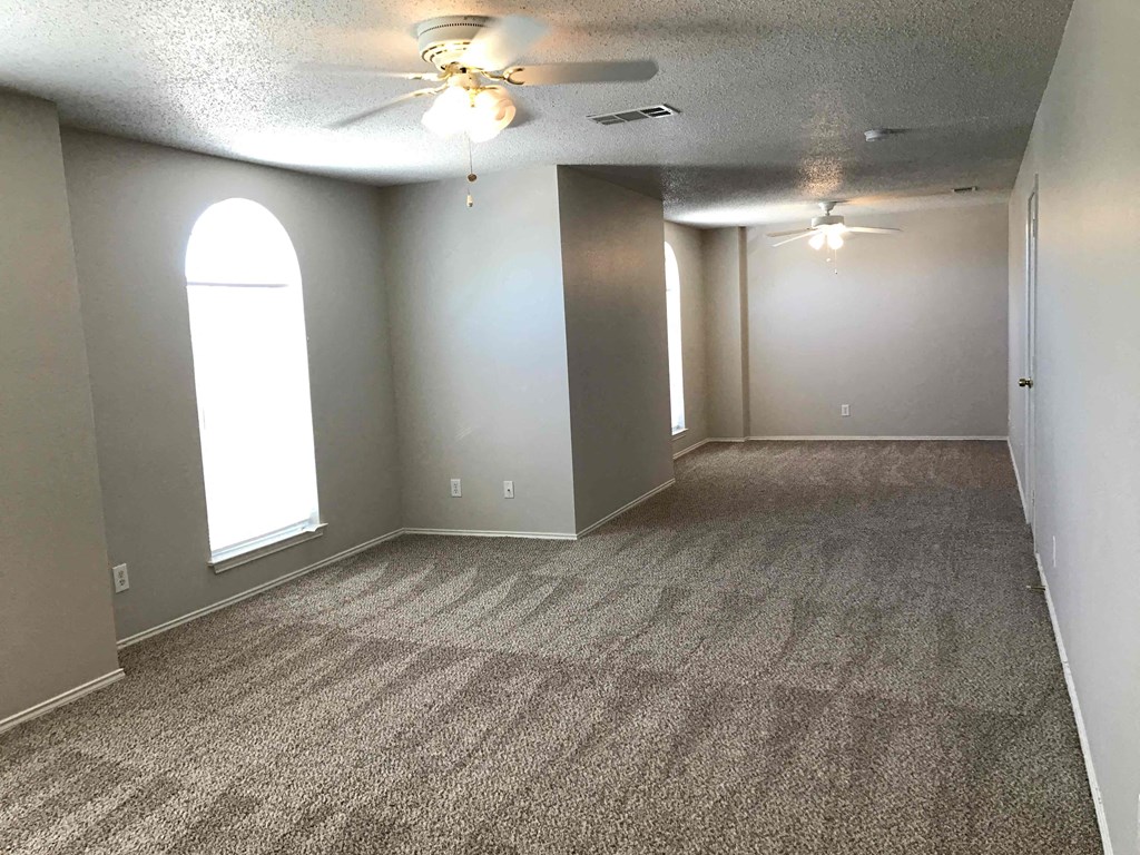 A room with a carpeted floor and a ceiling fan.