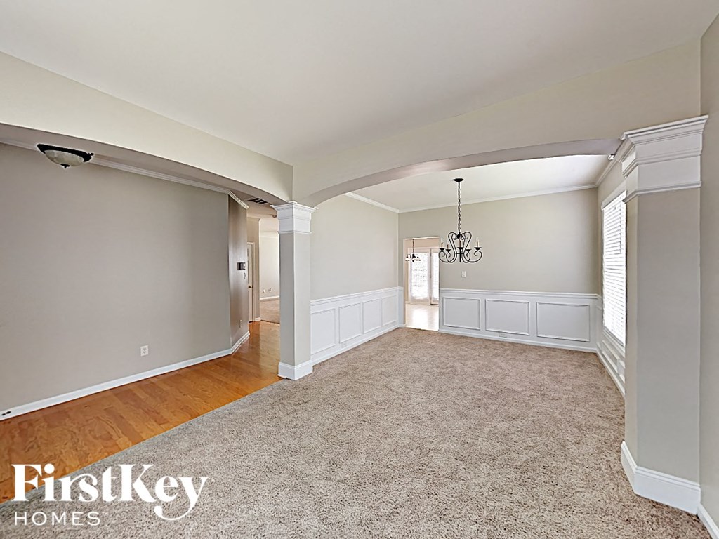 A spacious room with a carpeted floor and a chandelier hanging from the ceiling.