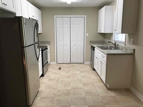 A kitchen with a black refrigerator and white cabinets.