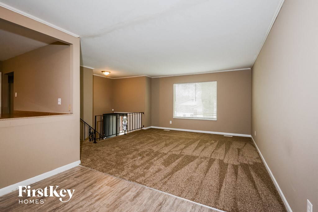 A room with a carpeted floor and a window with blinds.